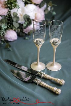 two champagne flutes and knife on a table with flowers