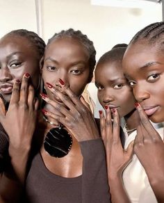 four models with their hands on their face and fingers in front of them, posing for the camera