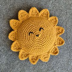 a crocheted sunflower is laying on the floor with its eyes closed and mouth wide open