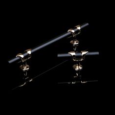 three pairs of black and gold cufflinks against a black background with reflection on the ground