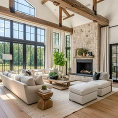 a living room filled with lots of furniture and large windows covered in wood beams