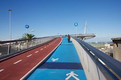 two people walking across a bridge with blue and red markings on the walkway next to them