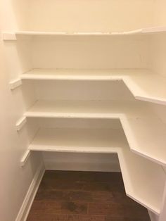 an empty white pantry with shelves and wood flooring in the corner, looking into the closet