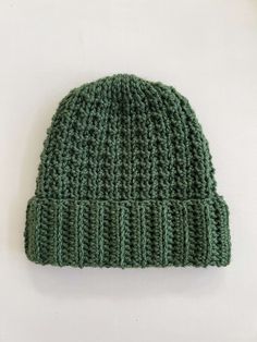 a green knitted hat sitting on top of a white table