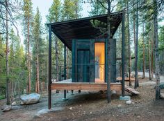 a small cabin in the woods with its door open