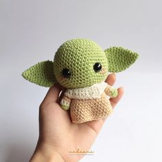 a small crocheted baby yoda doll is held in the palm of someone's hand