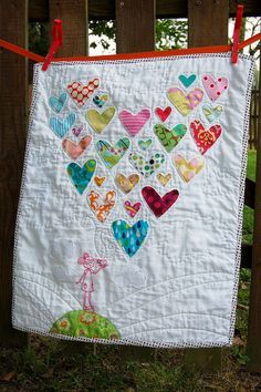 an image of a heart quilt hanging on a clothes line with the caption, i love this little quilt with hearts made from old baby clothes