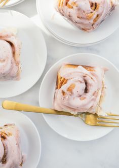 slices of cinnamon roll on white plates with gold forks