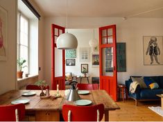 a dining room table with red chairs and an open door leading to the living room