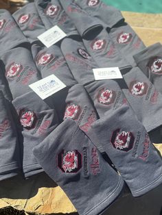 many gray shirts with red and white designs on them are sitting next to each other