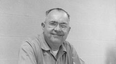 black and white photo of man with glasses smiling