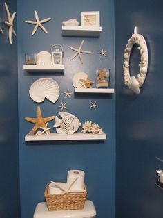 a bathroom with blue walls and white shelves filled with seashells, starfish, and shells