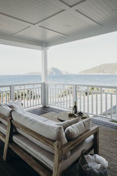 a couch sitting on top of a wooden floor next to a white fence and ocean