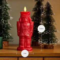 a red candle sitting on top of a wooden table next to christmas trees and pine cones