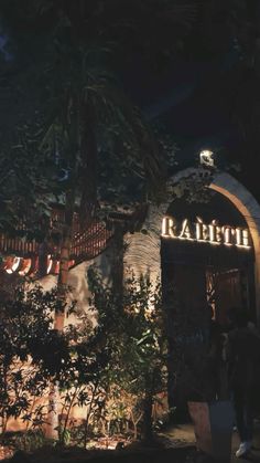 the entrance to radistro at night with people standing outside and trees in front