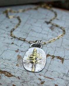 "Sterling and Gold Redwood Tree Necklace, Forest Necklace, Woodland Necklace, Artisan Necklace, Silver and Gold Nature Necklace I love trees of all kinds and showcase many in my Woods and Willow collections. But, by request, this is my first piece of the mighty Redwood tree! \"To walk in a redwood forest is to enter nature's cathedral.\" Above all, this tree symbolizes vitality and longevity, as it can grow to 1,000 years old and comes from a lineage of trees which grow into old ages This oval, Nature-inspired Engraved Pendant Necklaces, Nature-inspired Engraved Pendant Necklace, Hand Forged Nature-inspired Pendant Necklace, Nature-inspired Hand Forged Pendant Necklace, Nature-inspired Tree Of Life Pendant Necklace, Unique Tree Of Life Pendant Necklace, Tree Of Life Round Pendant Necklace, Unique Tree Of Life Round Pendant Necklace, Unique Sterling Silver Tree Of Life Necklace