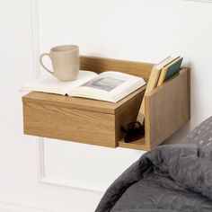 an open book, coffee cup and sunglasses on a bedside table next to a bed