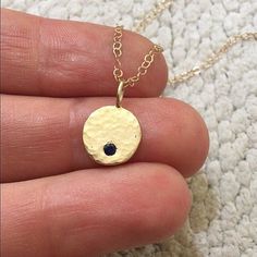 Handcrafted 14k yellow gold necklace with a pendant made of recycled gold. The scrap metal was melted into a chunk, hammered flat, stamped, polished, drilled, and given a hammered texture. A 2mm AA grade round faceted sapphire stone is flush set into the pendant. Comes on your choice of a 16 or 18 inch 14k yellow gold chain with the artist's tag attached at the clasp. (Shown on 16 inch chain on model) Can also be purchased as the pendant alone. Sapphire is the birthstone for September. Pendant m Gold Sapphire Round Pendant Jewelry, Hammered Yellow Gold Jewelry In Recycled Material, Hammered Yellow Gold Jewelry In Recycled Gold, Gold Sapphire Necklaces For Gift, Gold Sapphire Jewelry Stamped 14k, Gold Sapphire Round Pendant Necklace, Gold Sapphire Necklace For Gifting, Yellow Gold Birthstone Necklace In Recycled Gold, Gold Sapphire Necklace For Gift