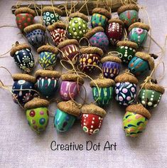 an assortment of colorful painted eggs on display with twine and burlocks attached to them