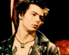 a young man wearing a leather jacket and necklace