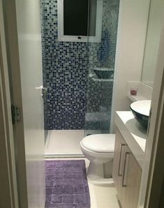 a white toilet sitting next to a sink in a bathroom under a tv mounted on the wall