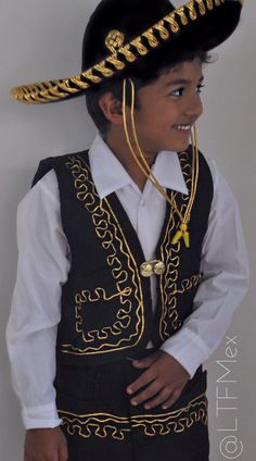 a young boy wearing a black and gold costume with a large hat on his head