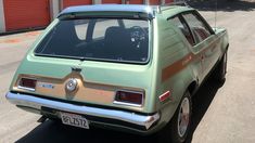 an old green car parked in front of a building