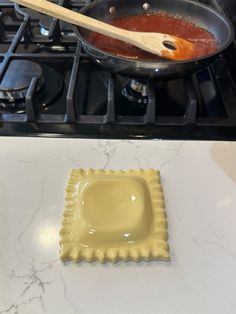 a pan with sauce and a wooden spoon on the stove