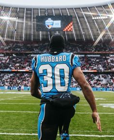 a man in a football uniform standing on the sidelines at a stadium with fans