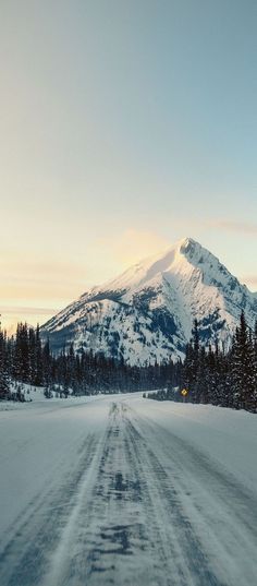 a snow covered road in front of a mountain