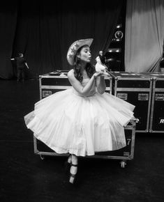 a woman in a dress and hat sitting on a stage