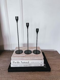 three black candlesticks sitting on top of two bookends, each with one candle