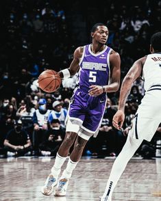 two basketball players in action on the court with fans watching from the stands behind them