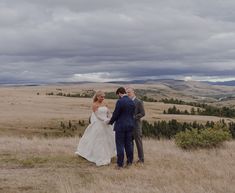 a bride and groom standing in the middle of a field