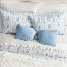 a bed with blue and white pillows on it's headboard, along with two pillow cases