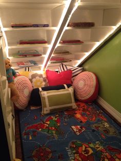 there are stuffed animals and pillows in the room under the stairs with lights on them