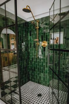 a green tiled bathroom with black and white tile flooring, shower head, and mirror