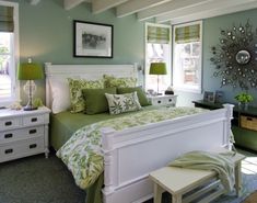 a bedroom with green and white bedding, pillows and decor on the walls is pictured in this image