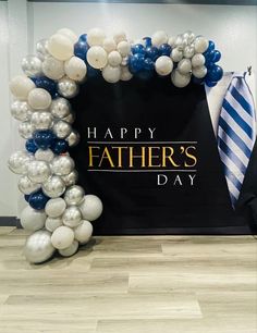 a father's day balloon arch with balloons and a tie on the floor in front of it