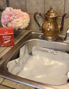 a kitchen sink filled with ice and water next to a box of baking soda on the counter