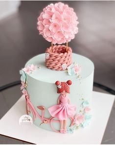 a cake decorated with pink flowers and a girl on a scooter is shown