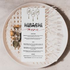 a menu on a plate with flowers and utensils next to it that says hibachi menu