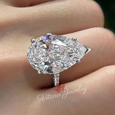 a close up of a person's hand holding a diamond ring