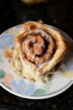 a cinnamon roll sitting on top of a white and blue plate covered in icing