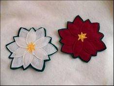 two flower appliques sitting on top of a white cloth covered table next to each other