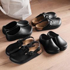 four pairs of black shoes sitting on top of a wooden floor