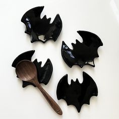 three black dishes with wooden spoons and bats on them, one is empty or half