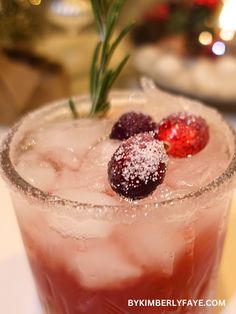 a close up of a drink in a glass with ice and strawberries on the rim