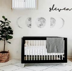 a baby's room with a crib and moon decals on the wall