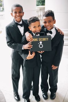 three young boys in tuxedos holding up a sign that says ring security on it